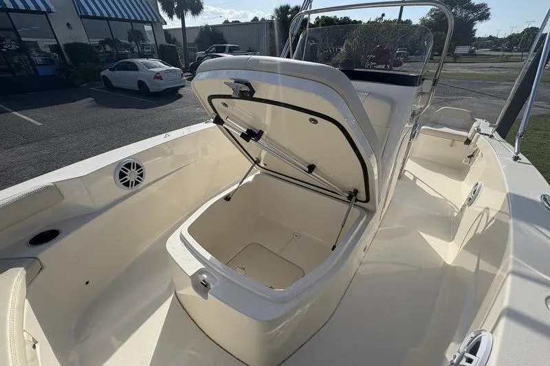 Slide: The Image of 2026 Scout 188 Sportfish boat with open storage compartment, parked outdoors. - 21