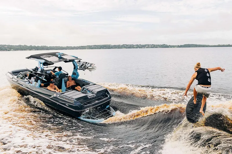Slide: The Image of Manufacturer Provided Image: 2025 Supra SL boat towing a wakeboarder on a lake, showcasing water sports action. - 21