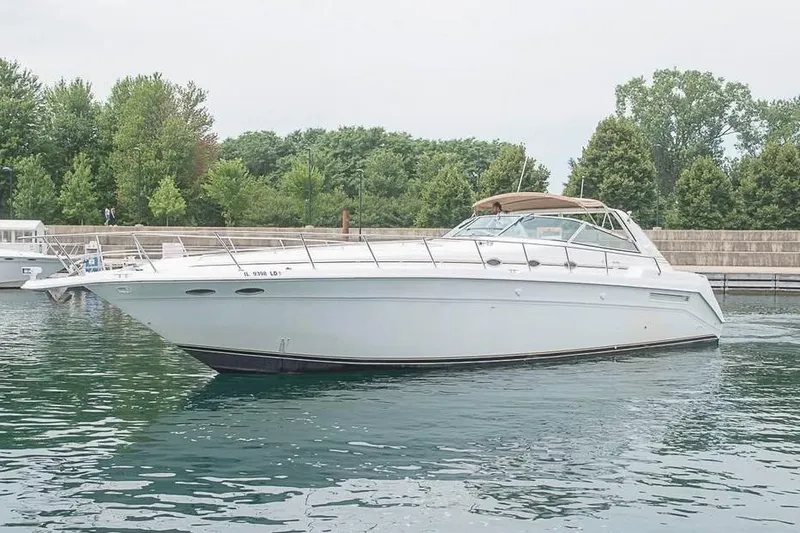 Slide: The Image of 1998 Sea Ray 500 Sundancer yacht on calm water near a lush shoreline. - 2