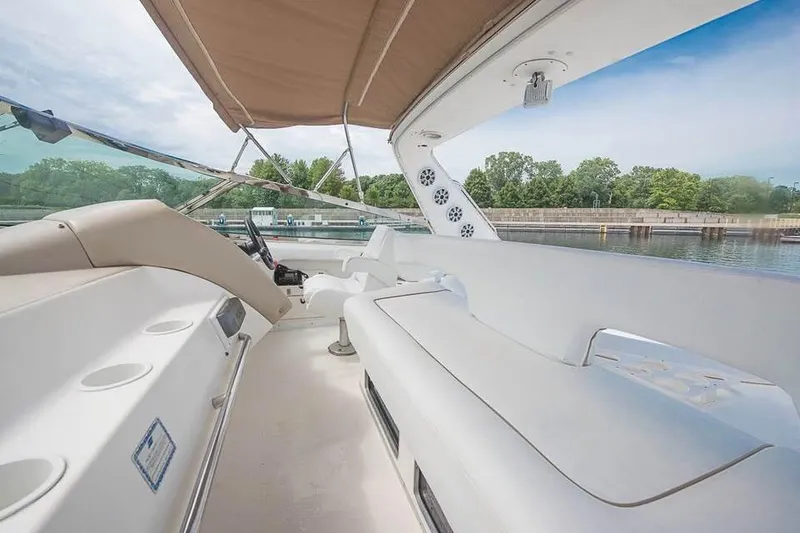 Slide: The Image of 1998 Sea Ray 500 Sundancer yacht interior with spacious seating and canopy, docked by a serene waterfront. - 6