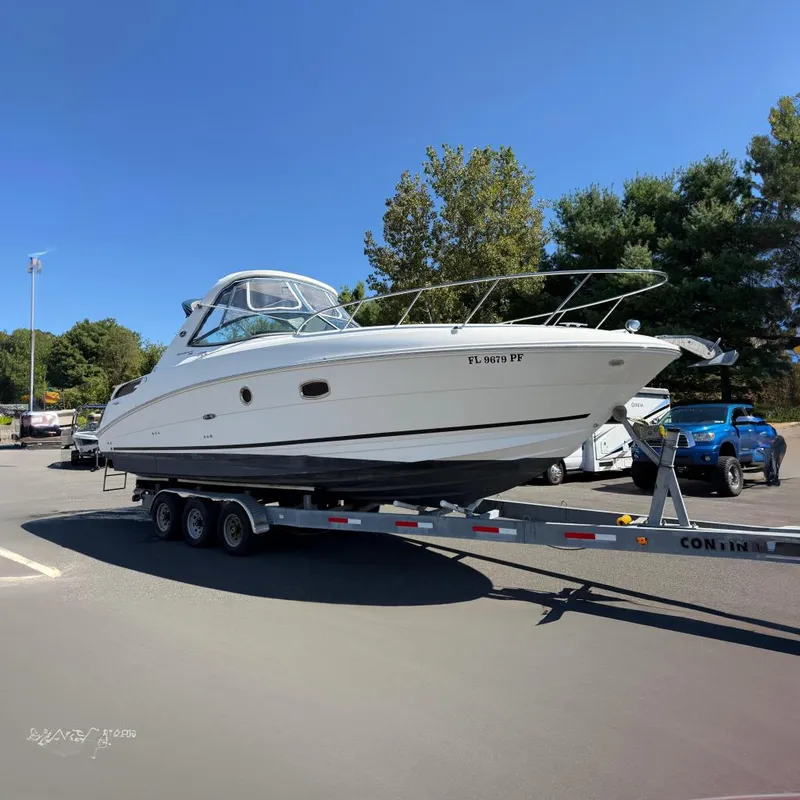 The Image of 2010 Sea Ray 310 Sundancer boat on trailer in parking lot, clear sky background. - 0