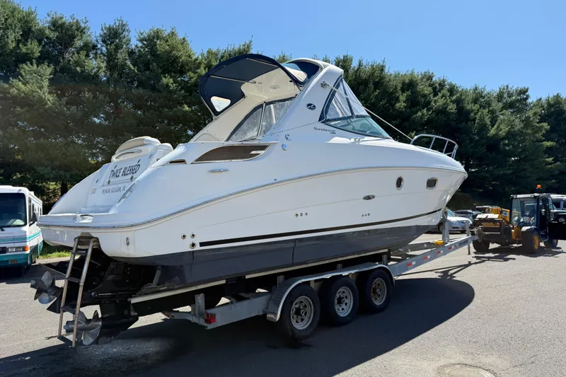 Slide: The Image of 2010 Sea Ray 310 Sundancer boat on trailer, parked outdoors under clear blue sky. - 2