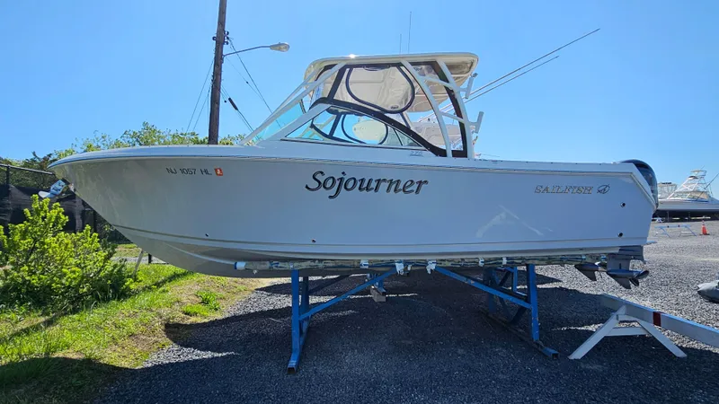 Slide: The Image of 2019 Sailfish 275 DC boat named "Sojourner" on a trailer, parked outdoors. - 0
