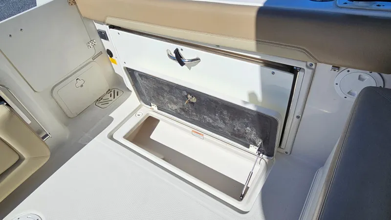 Slide: The Image of Open storage compartment on 2019 Sailfish 275 DC boat, featuring beige and white interior. - 17