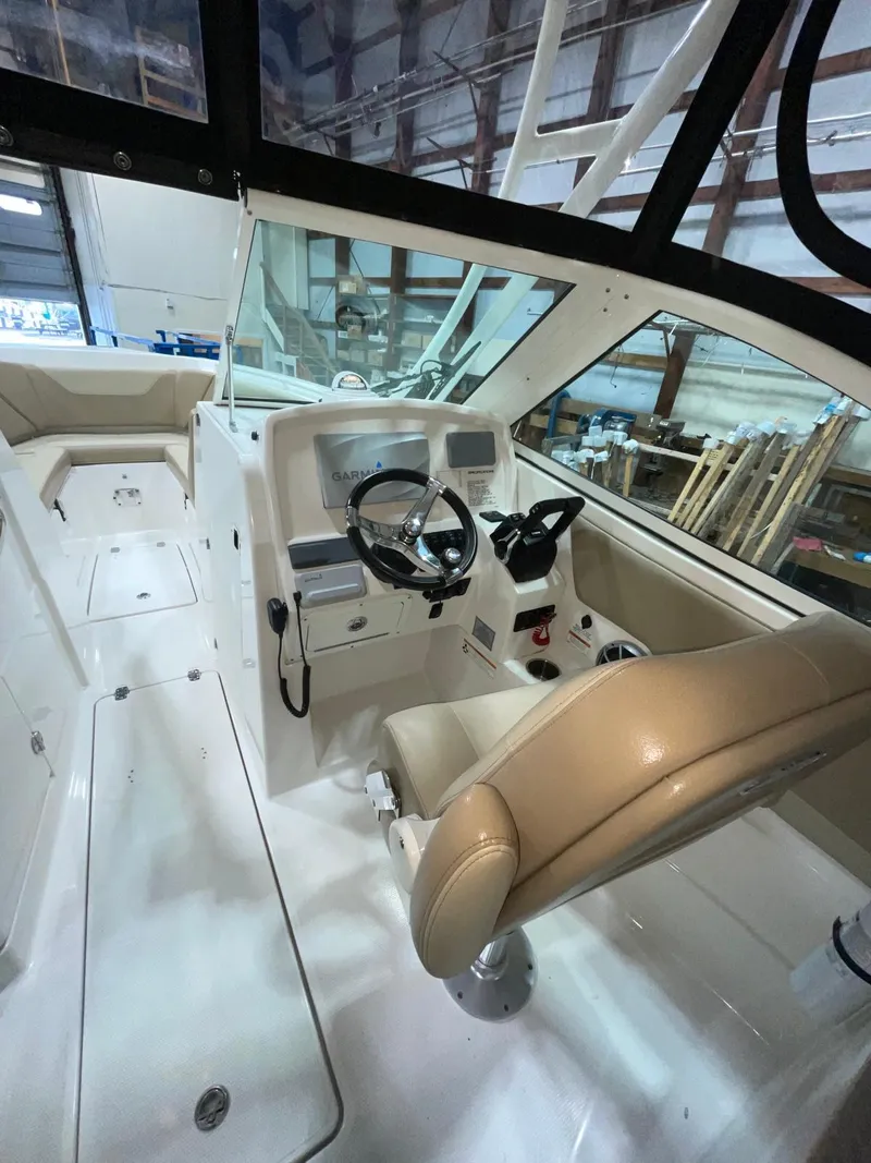 Slide: The Image of 2019 Sailfish 275 DC boat interior with steering wheel and seating in a warehouse setting. - 22