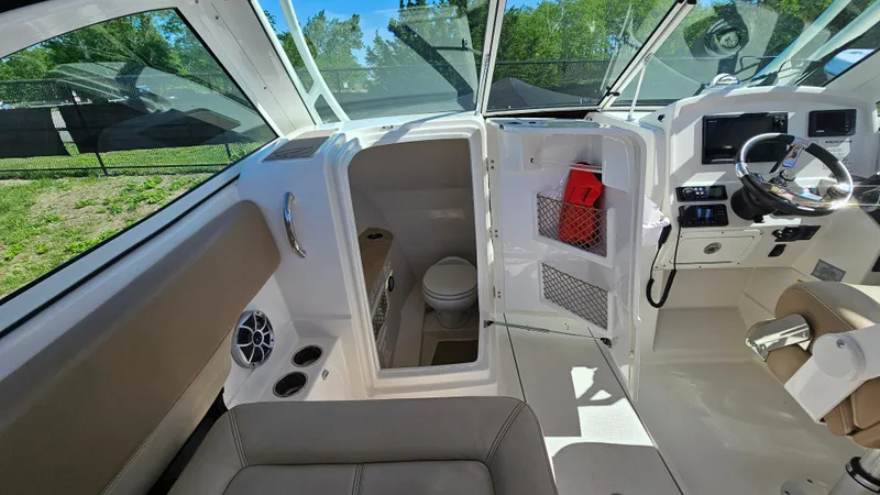 Slide: The Image of 2019 Sailfish 275 DC boat interior with helm, seating, and compact restroom. - 28