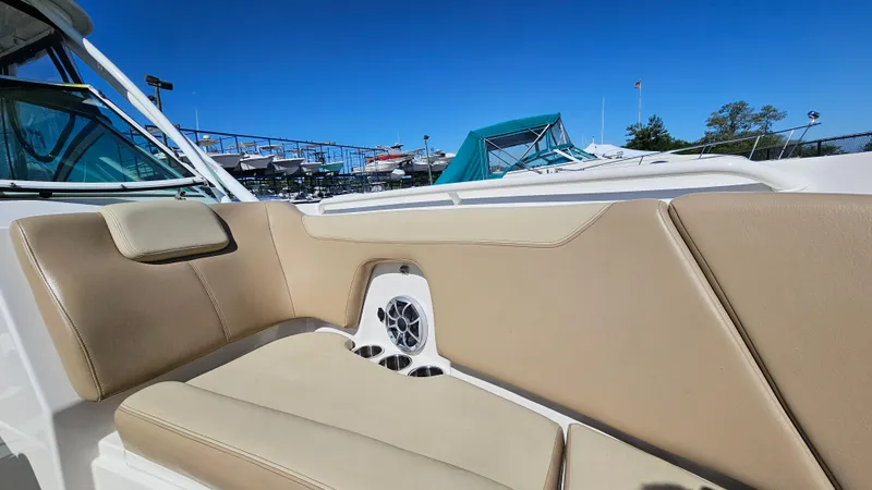 Slide: The Image of 2019 Sailfish 275 DC boat with beige seating and speaker, docked under clear blue sky. - 33