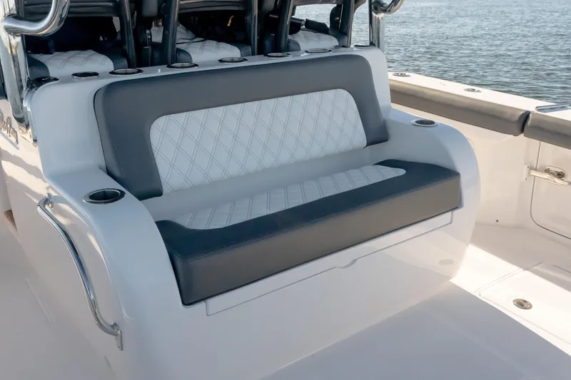 Slide: The Image of 2026 Mag Bay 43 CC boat seating with diamond-stitched upholstery and cup holders, on calm water. - 17