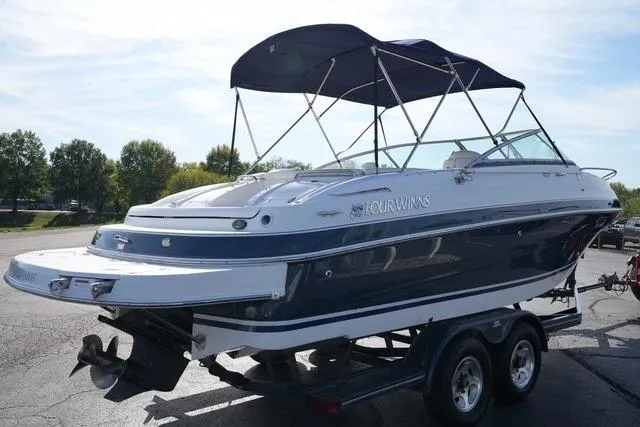 Slide: The Image of 2004 Four Winns 245 Sundowner boat on trailer, featuring a sleek design and canopy. - 4