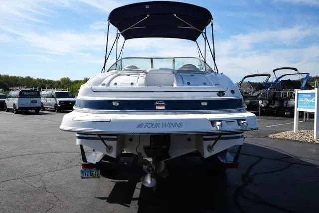 Slide: The Image of 2004 Four Winns 245 Sundowner boat with canopy, parked on asphalt under blue sky. - 5