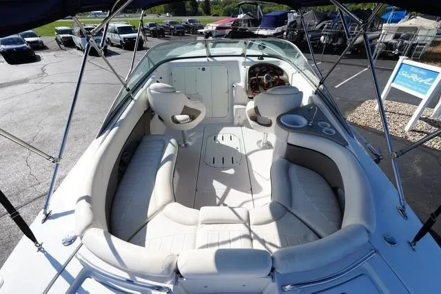 Slide: The Image of 2004 Four Winns 245 Sundowner boat interior with seating and steering wheel, parked outdoors. - 7