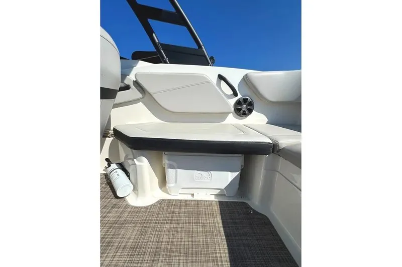 Slide: The Image of 2021 Sea Ray SPX 210 Outboard interior with seating and storage, under clear blue sky. - 10