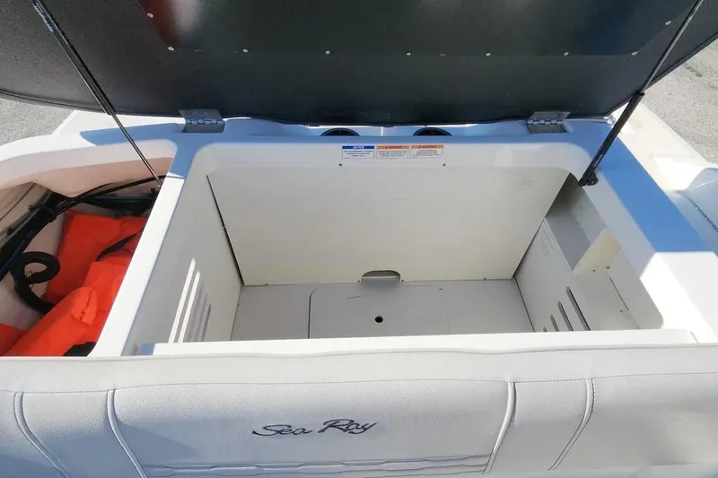 Slide: The Image of 2021 Sea Ray SPX 210 Outboard boat storage compartment with open lid and visible life jackets. - 17