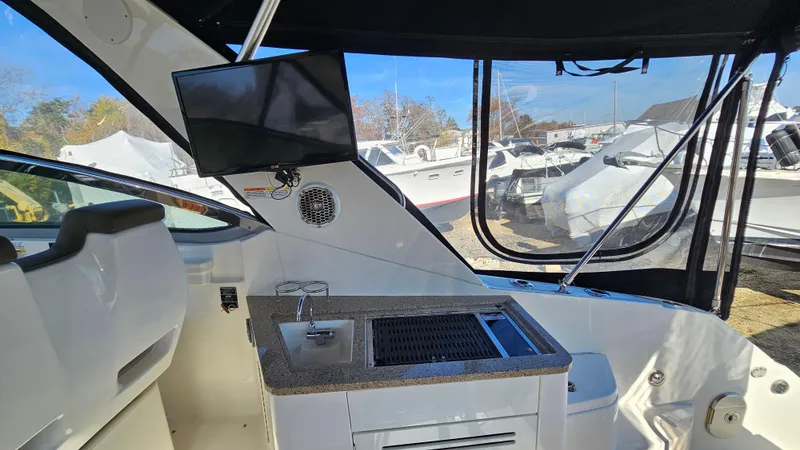 Slide: The Image of 2014 Sea Ray 350 Sundancer interior with kitchenette and mounted TV. - 9