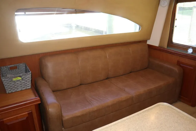 Slide: The Image of 2005 Luhrs 38 Convertible interior with brown leather sofa and window view. - 35
