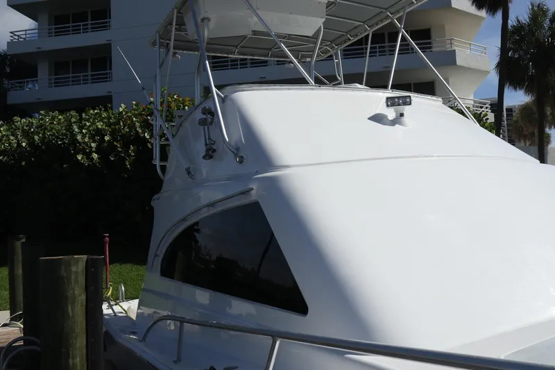 Slide: The Image of 2005 Luhrs 38 Convertible yacht docked near modern building and lush greenery. - 64