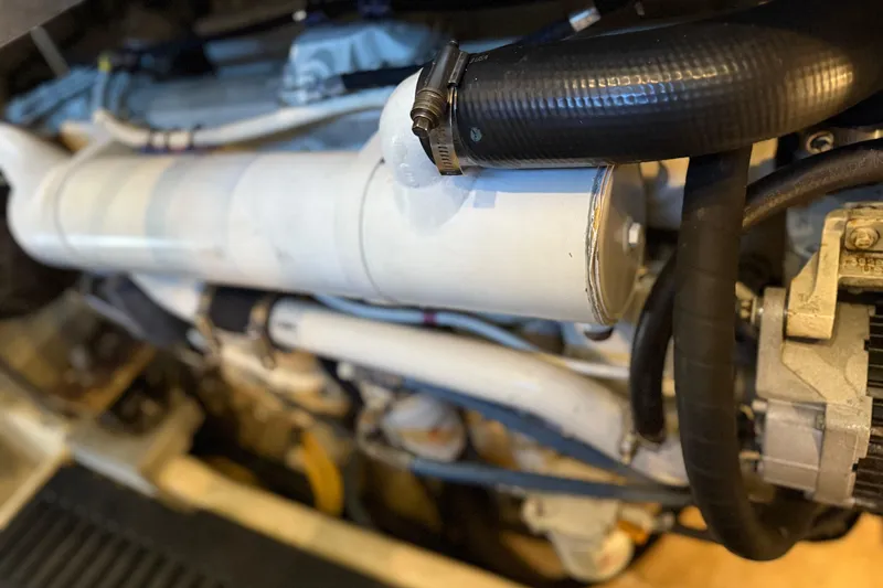 Slide: The Image of Engine components of a 2005 Luhrs 38 Convertible boat, featuring hoses and metal parts. - 70