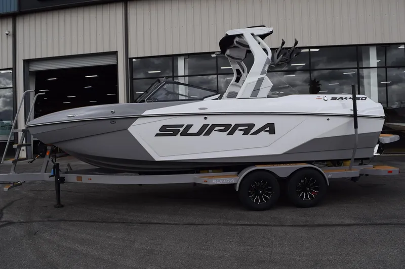 Slide: The Image of 2025 Supra SA boat on trailer, parked outside a building. - 1