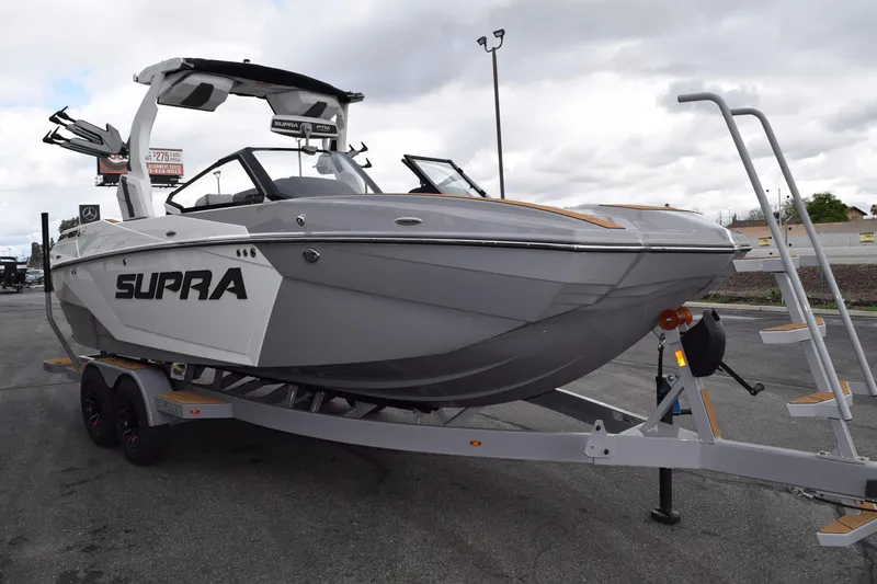 Slide: The Image of 2025 Supra SA boat on trailer, sleek design, gray color, parked outdoors. - 2