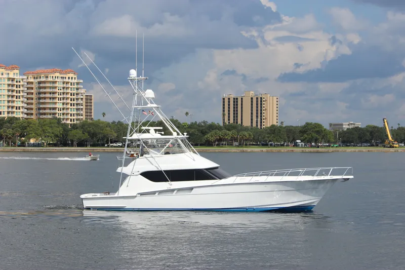 Slide: The Image of 2004 Hatteras 60 Convertible yacht on calm water with cityscape background. - 2