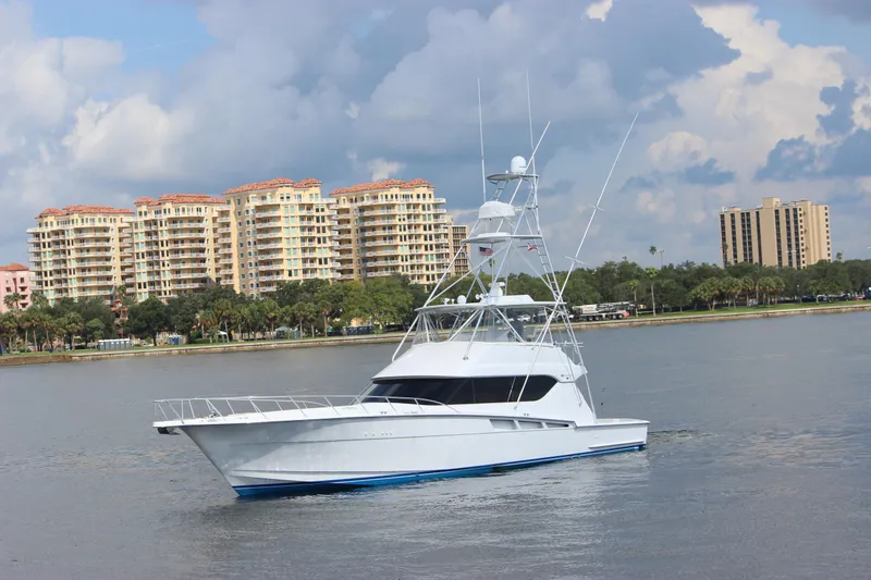 Slide: The Image of 2004 Hatteras 60 Convertible yacht on calm water with cityscape background. - 3