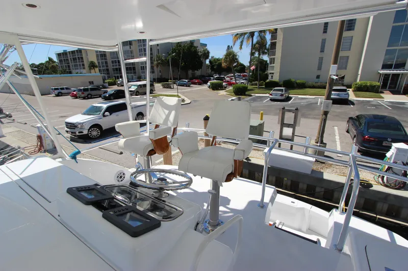 Slide: The Image of 2004 Hatteras 60 Convertible yacht helm with seating, docked in a marina parking area. - 38
