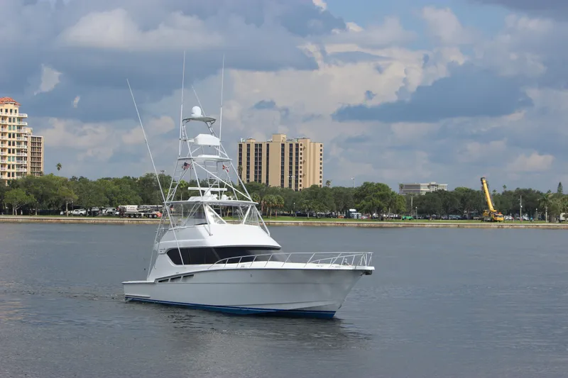 Slide: The Image of 2004 Hatteras 60 Convertible yacht on calm water with cityscape background. - 4