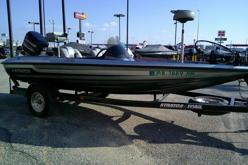 Slide: The Image of 1998 Stratos 273 V boat on trailer in parking lot, featuring Johnson V6 engine. - 14