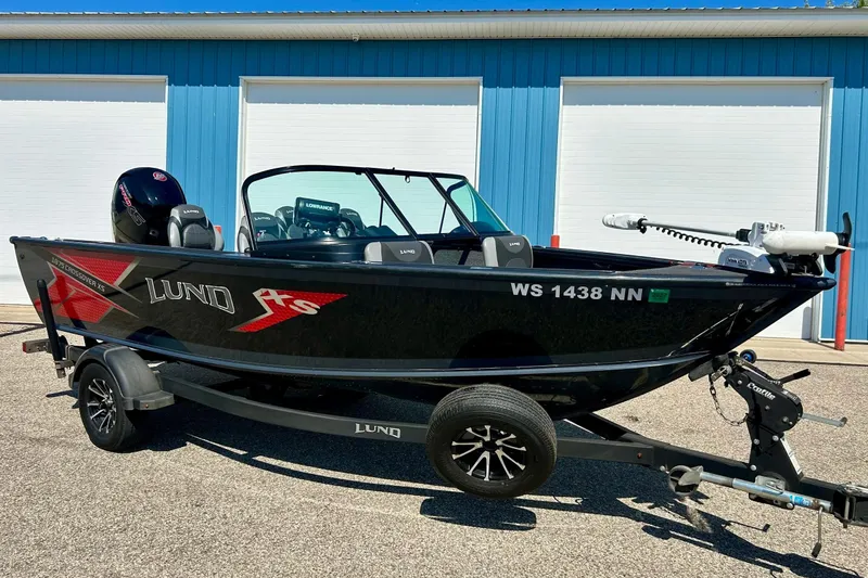 Slide: The Image of 2021 Lund 1875 Crossover XS boat on trailer, parked outside blue building. - 0