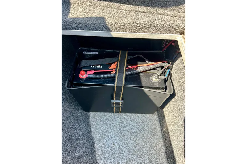 Slide: The Image of Battery compartment in 2021 Lund 1875 Crossover XS boat, featuring a secured Li Time battery. - 28