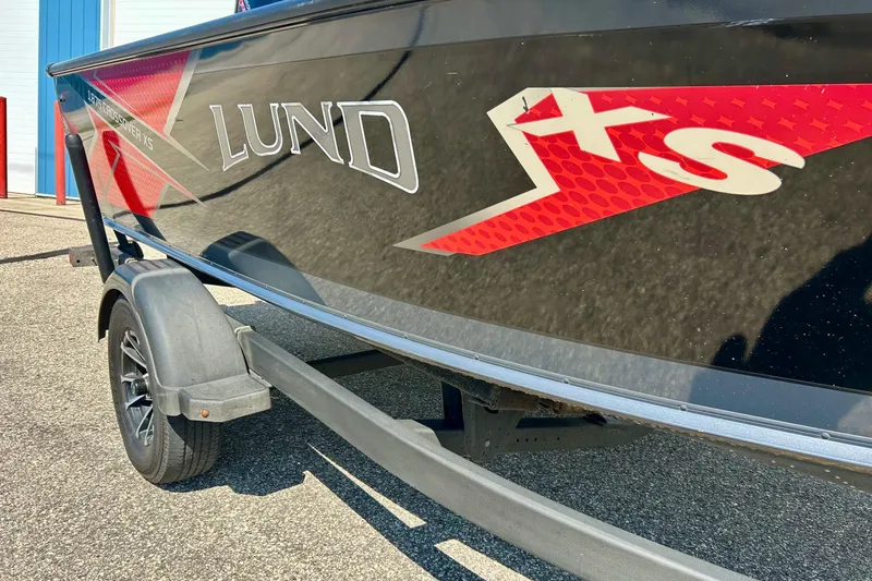Slide: The Image of 2021 Lund 1875 Crossover XS boat on trailer, featuring sleek black and red design. - 3
