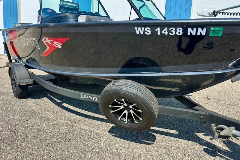Slide: The Image of 2021 Lund 1875 Crossover XS boat on trailer, black exterior, parked outdoors. - 44