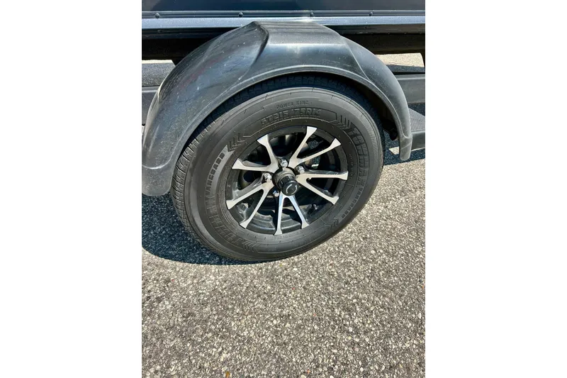 Slide: The Image of 2021 Lund 1875 Crossover XS trailer wheel on asphalt surface. - 5