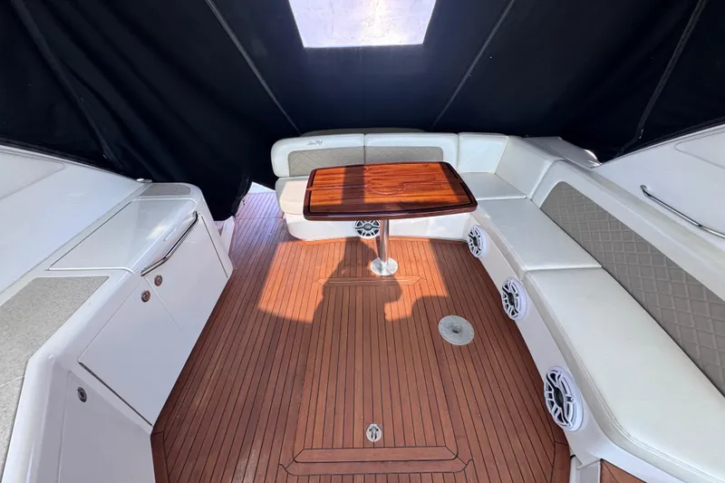 Slide: The Image of 2011 Sea Ray 540 Sundancer interior with wood table, white seating, and teak flooring. - 14