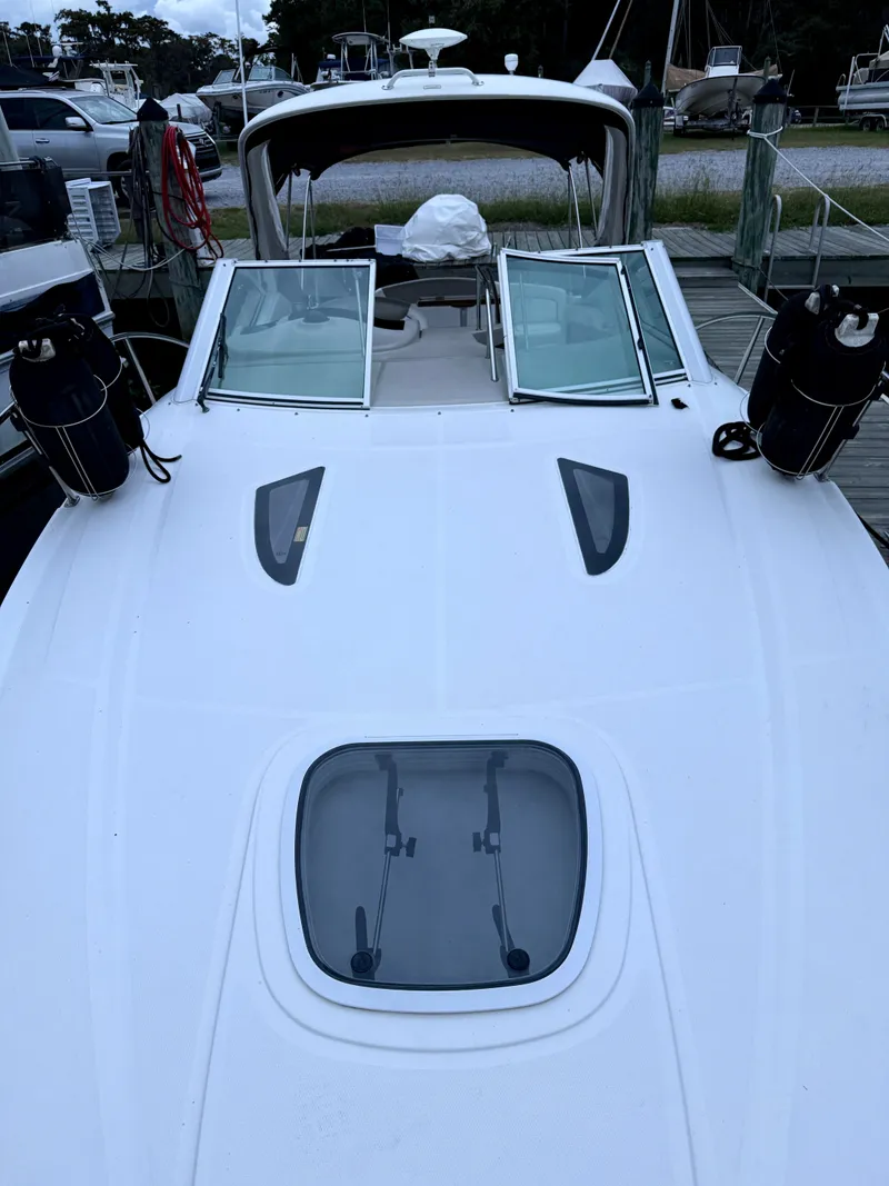 Slide: The Image of 2006 Sea Ray 290 Sundancer boat docked, featuring open deck and windshield. - 36