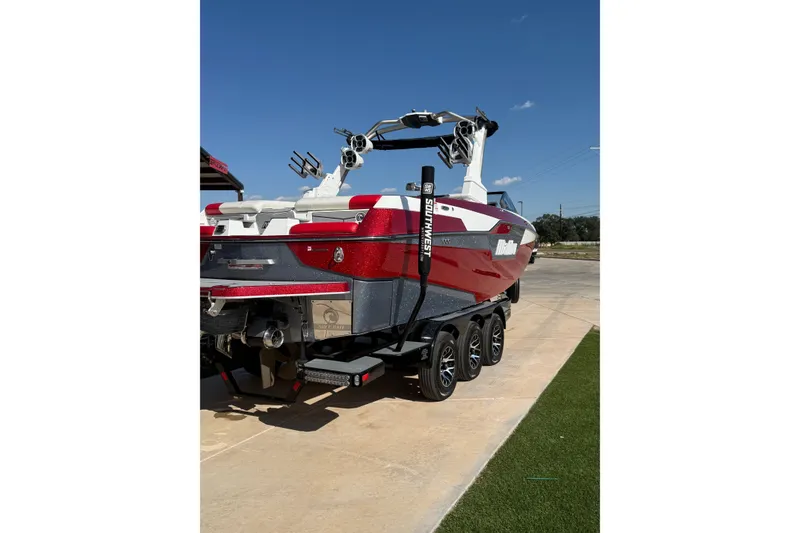 Slide: The Image of Red 2021 Malibu M240 boat on trailer under clear blue sky. - 18