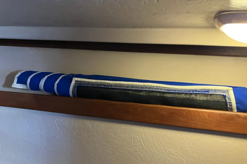 Slide: The Image of Rolled blue sail stored on a wooden shelf inside a 1985 Catalina 30 boat. - 39