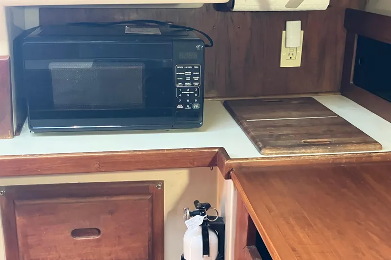 Slide: The Image of Kitchen area of a 1985 Catalina 30 sailboat with microwave and cutting board. - 28