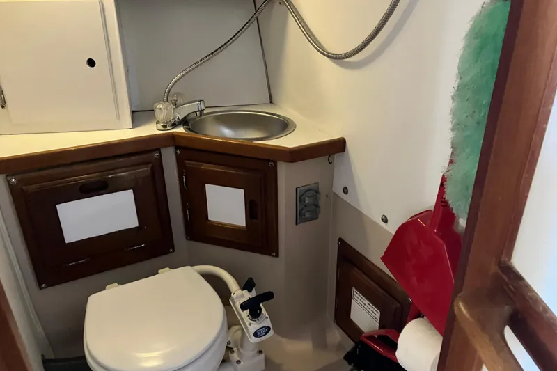 Slide: The Image of 1985 Catalina 30 boat bathroom with sink, toilet, and storage cabinets. - 31