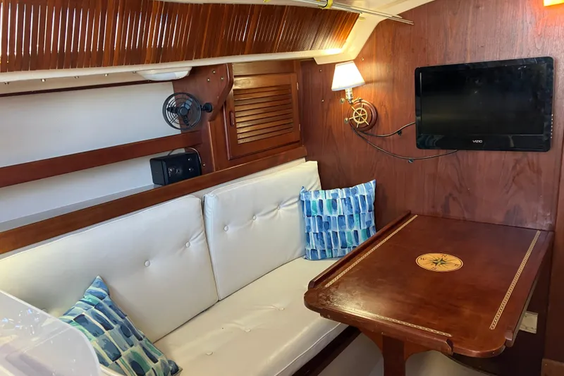 Slide: The Image of Interior of 1985 Catalina 30 sailboat with cozy seating, table, and mounted TV. - 21