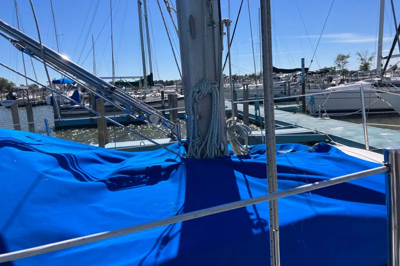 Slide: The Image of 1985 Catalina 30 sailboat with blue cover docked at marina under clear sky. - 4