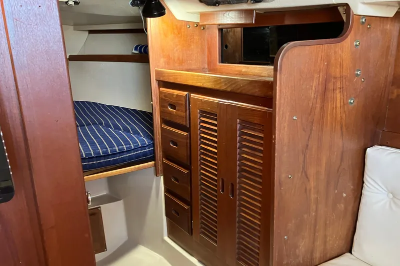 Slide: The Image of Interior of 1985 Catalina 30 sailboat with wooden cabinetry and blue-striped bedding. - 27
