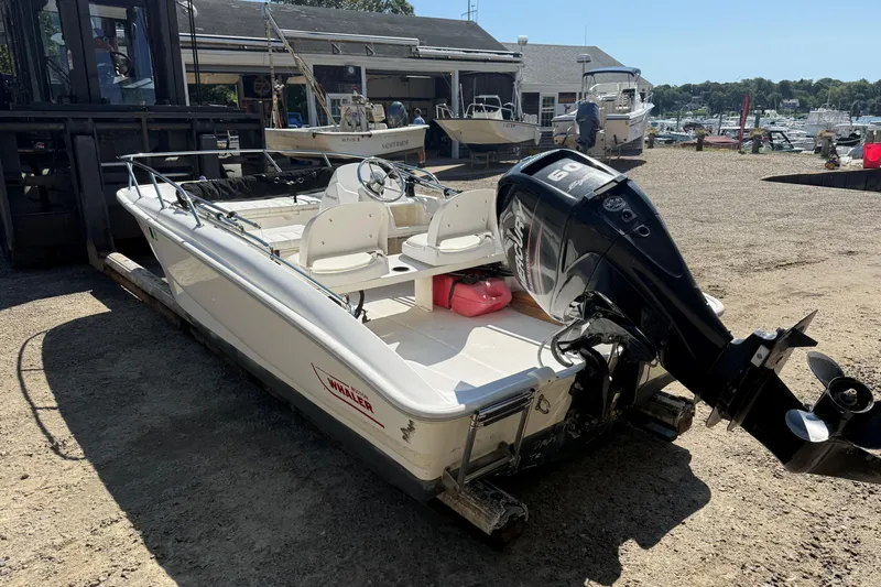 Slide: The Image of 2013 Boston Whaler 150 Super Sport boat with outboard motor in a marina setting. - 3