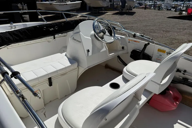 Slide: The Image of 2013 Boston Whaler 150 Super Sport boat interior with steering wheel and seating. - 7