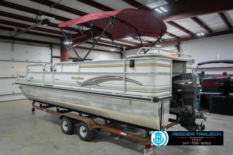 Slide: The Image of 1999 Landau DX24 pontoon boat with Johnson outboard motor in indoor storage. - 10