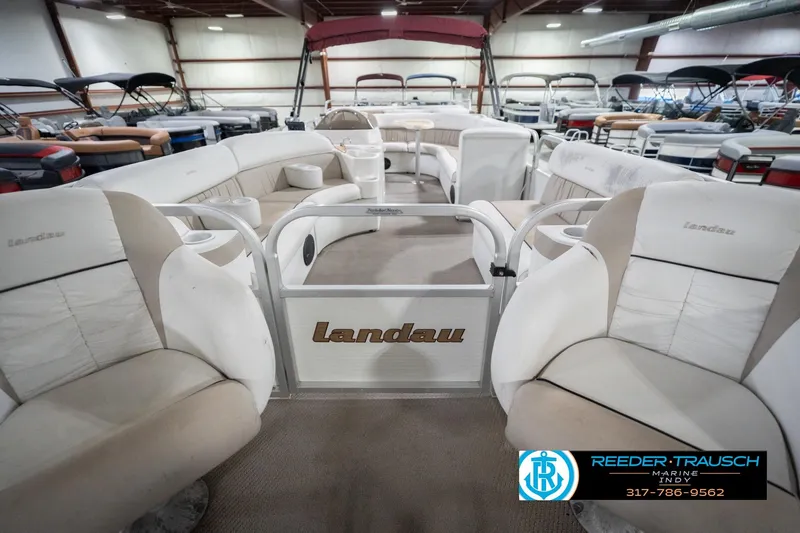 Slide: The Image of 1999 Landau DX24 pontoon boat interior with beige seating in a showroom. - 16