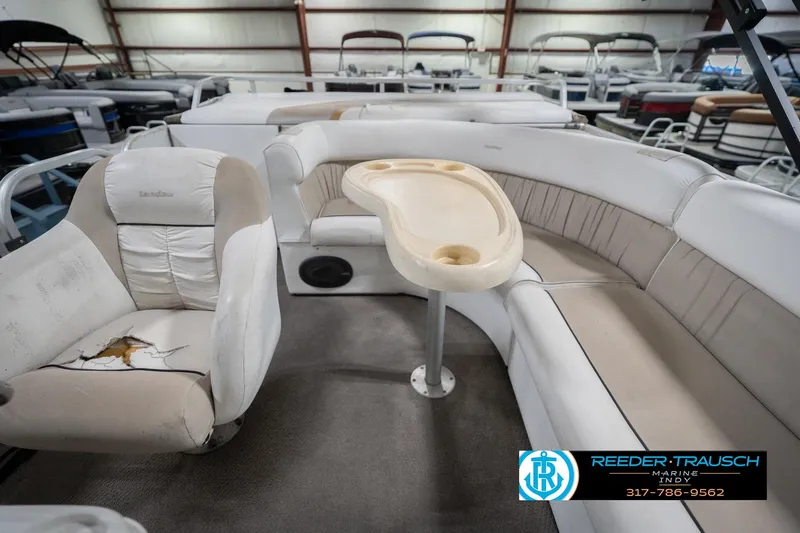 Slide: The Image of Interior of a 1999 Landau DX24 pontoon boat with worn seating and a central table. - 18