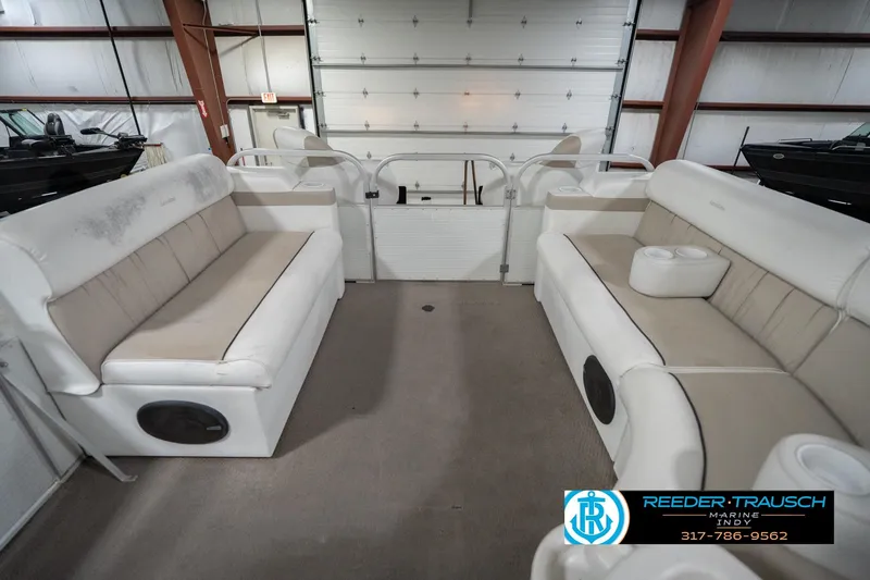 Slide: The Image of Interior of a 1999 Landau DX24 pontoon boat with beige seating and cup holders. - 20