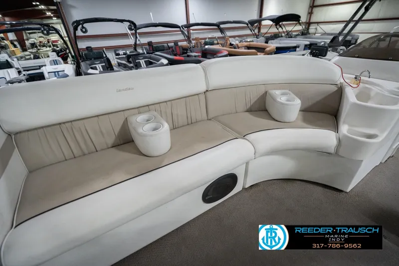 Slide: The Image of 1999 Landau DX24 boat interior with beige seating and cup holders in showroom. - 24