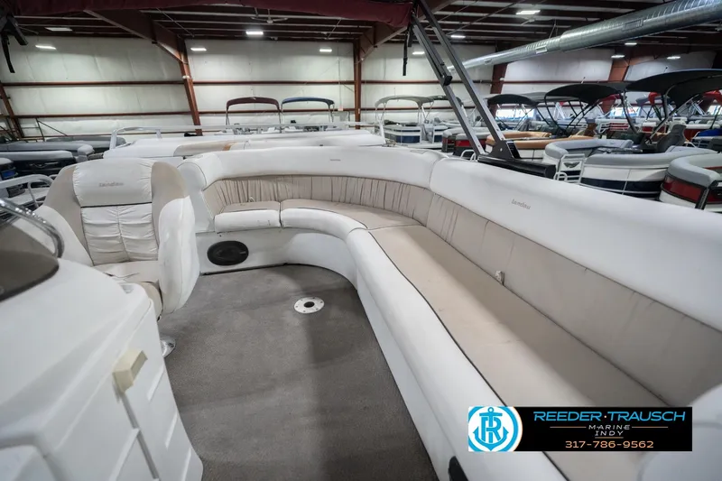 Slide: The Image of 1999 Landau DX24 pontoon boat interior with beige seating in a showroom. - 28
